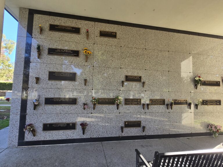 Heritage Mausoleum - Deluxe Companion Crypt featuring a large stone wall with multiple crypt slots adorned with flowers.