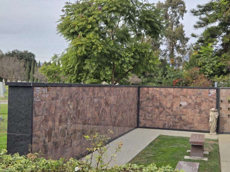 Mountain View Columbarium - Companion Niche featuring a stone wall with niches, a bench, and green landscaping.