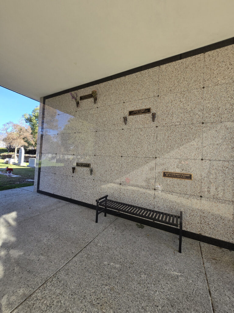 Heritage Mausoleum - Single Crypt with a stone wall, empty crypt slots, and a bench nearby.