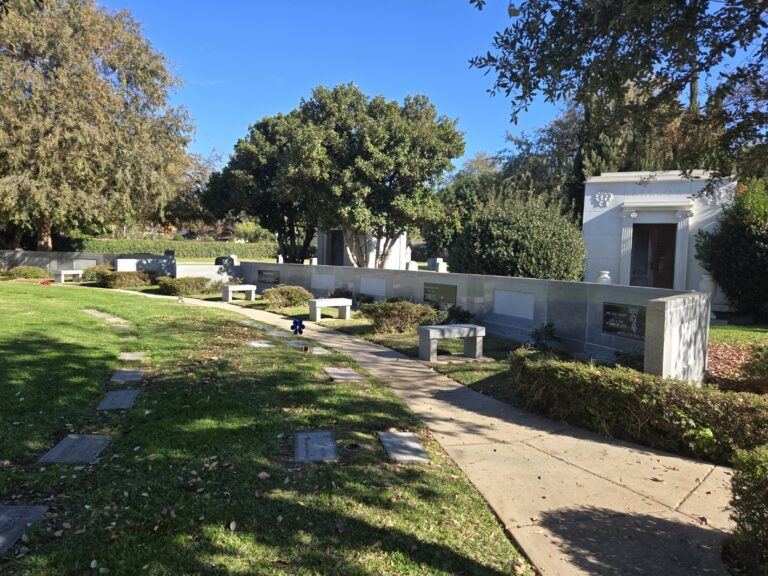 Block V - Family Estate featuring a cemetery lawn with gravestones, pathways, benches, and a mausoleum surrounded by trees.